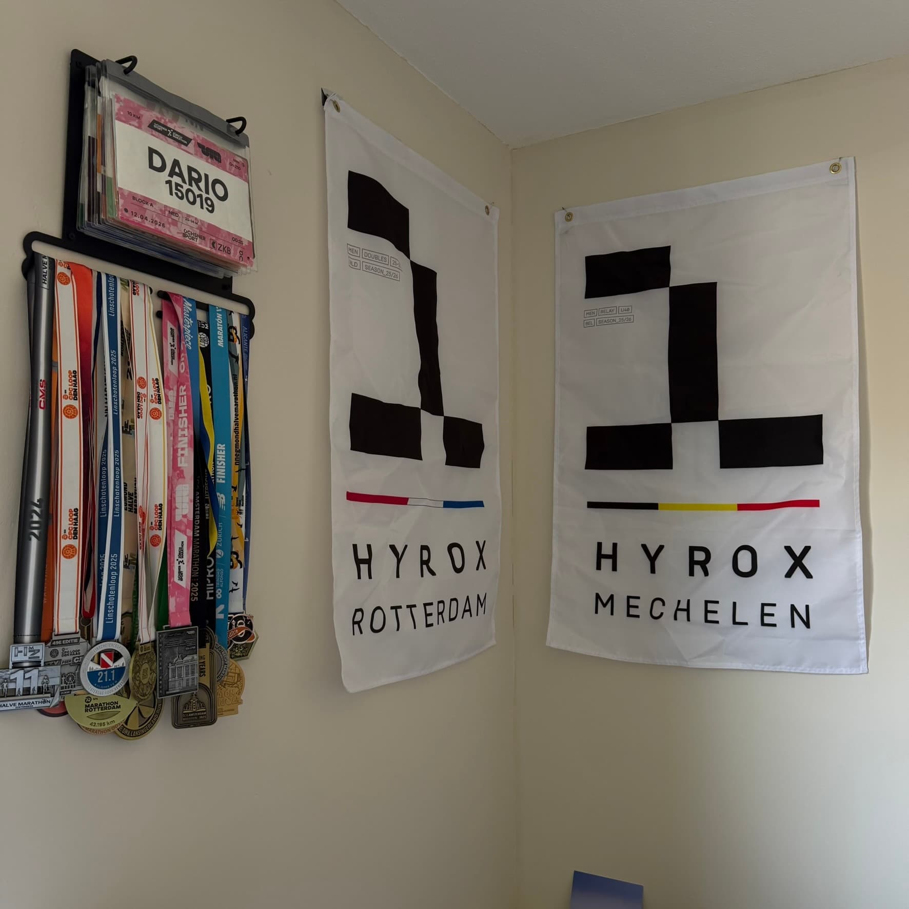 De racemedailles en HYROX-vlaggen in Dario's coachingwerkplek